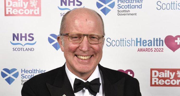  Mr. Andrew Kent, 58 years old, proudly holds his trophy donned in a suit jacket, shirt, bow tie and kilt.