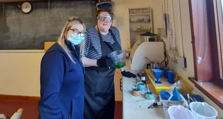 An Isobel Rhind worker and a supported person standing beside a candle making station.